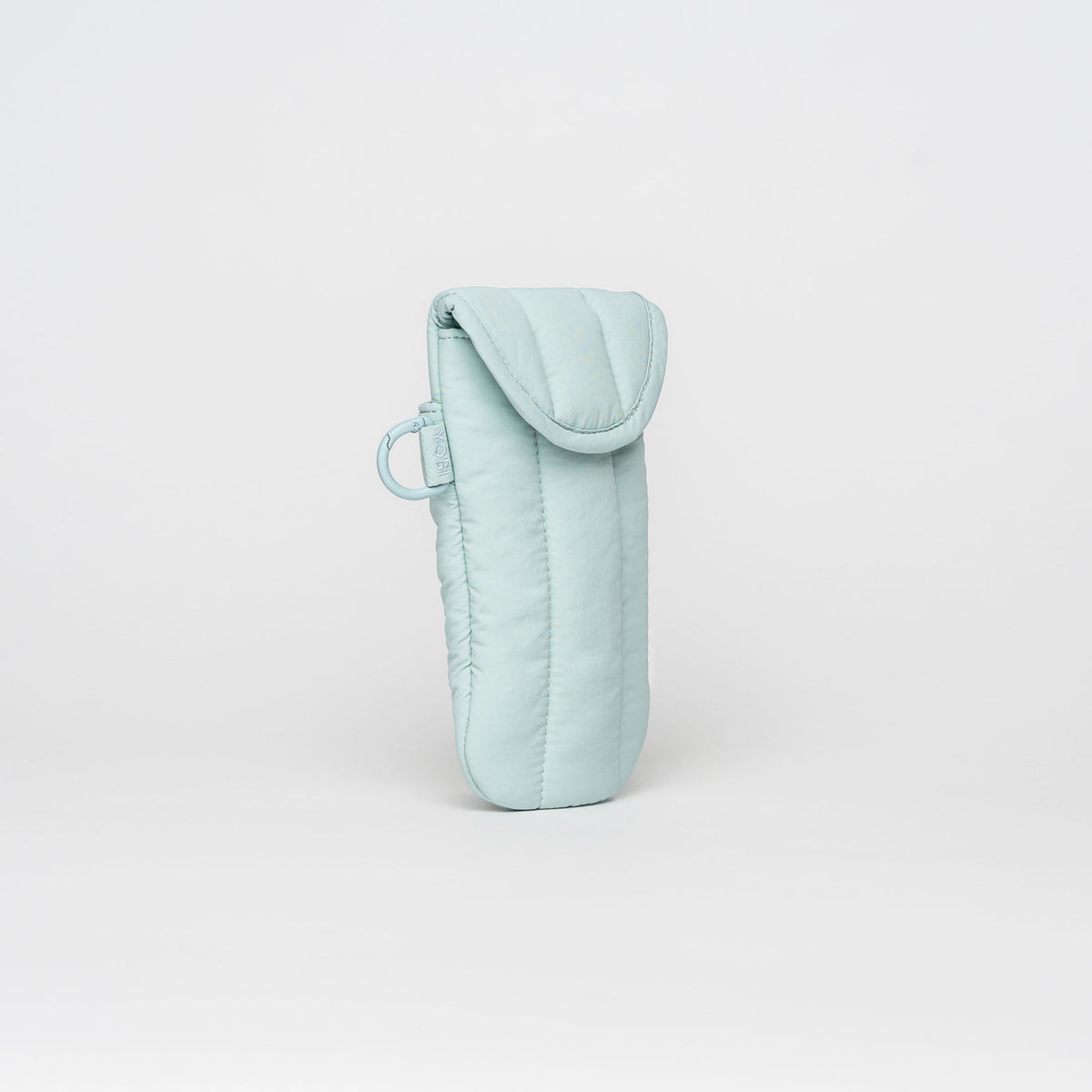 A light mint green quilted fabric pouch with a flap closure and a small matching loop, standing upright on a seamless light gray background.