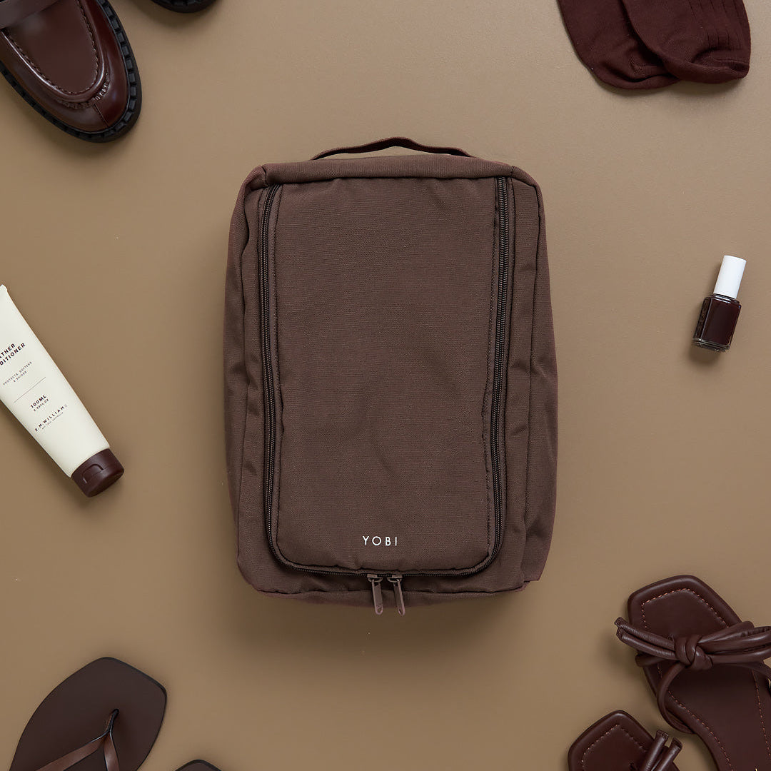 Brown travel shoe bag with Yobi branding on a beige background with shoes and toiletries.