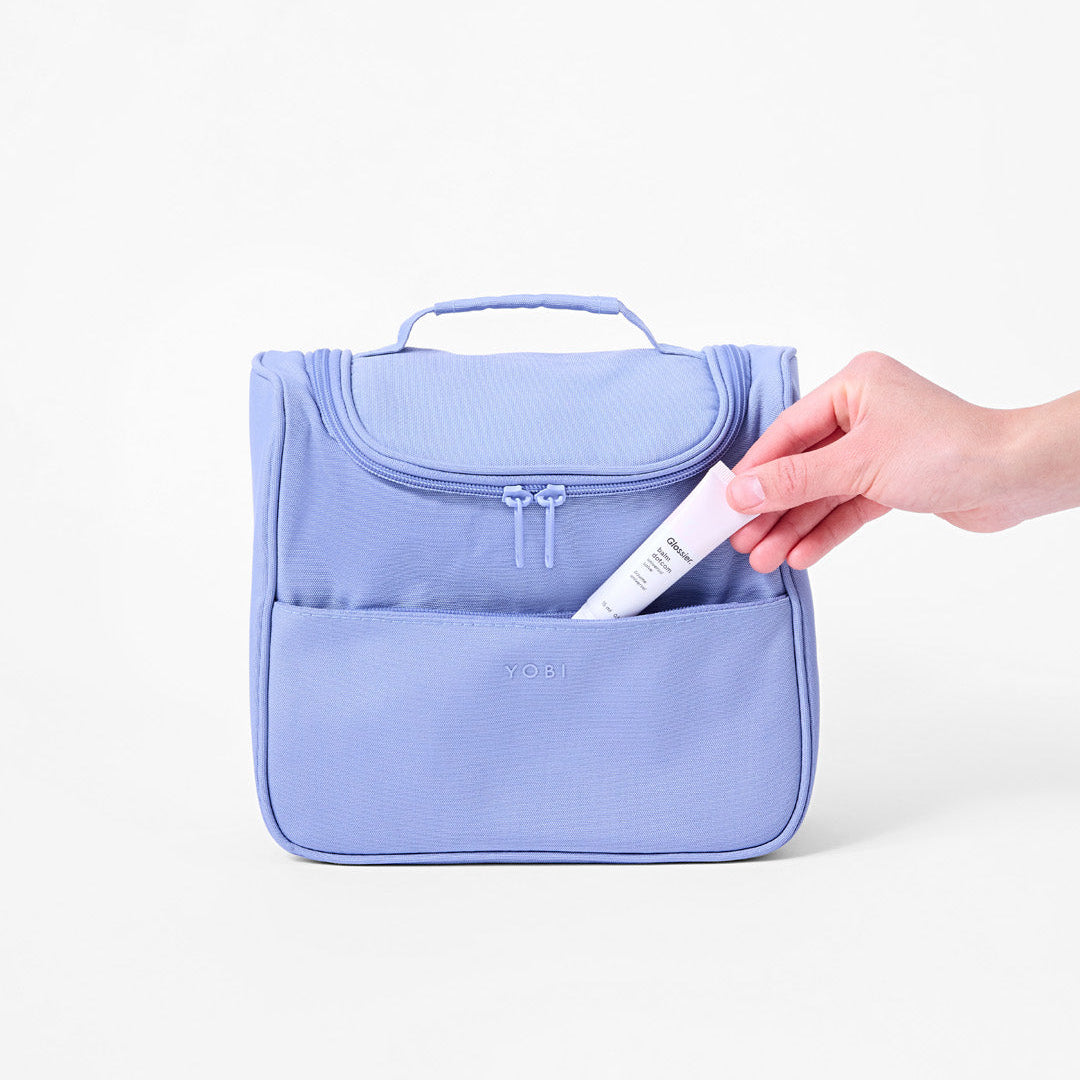 Inserting lip balm into front pocket of Toiletry Bag
