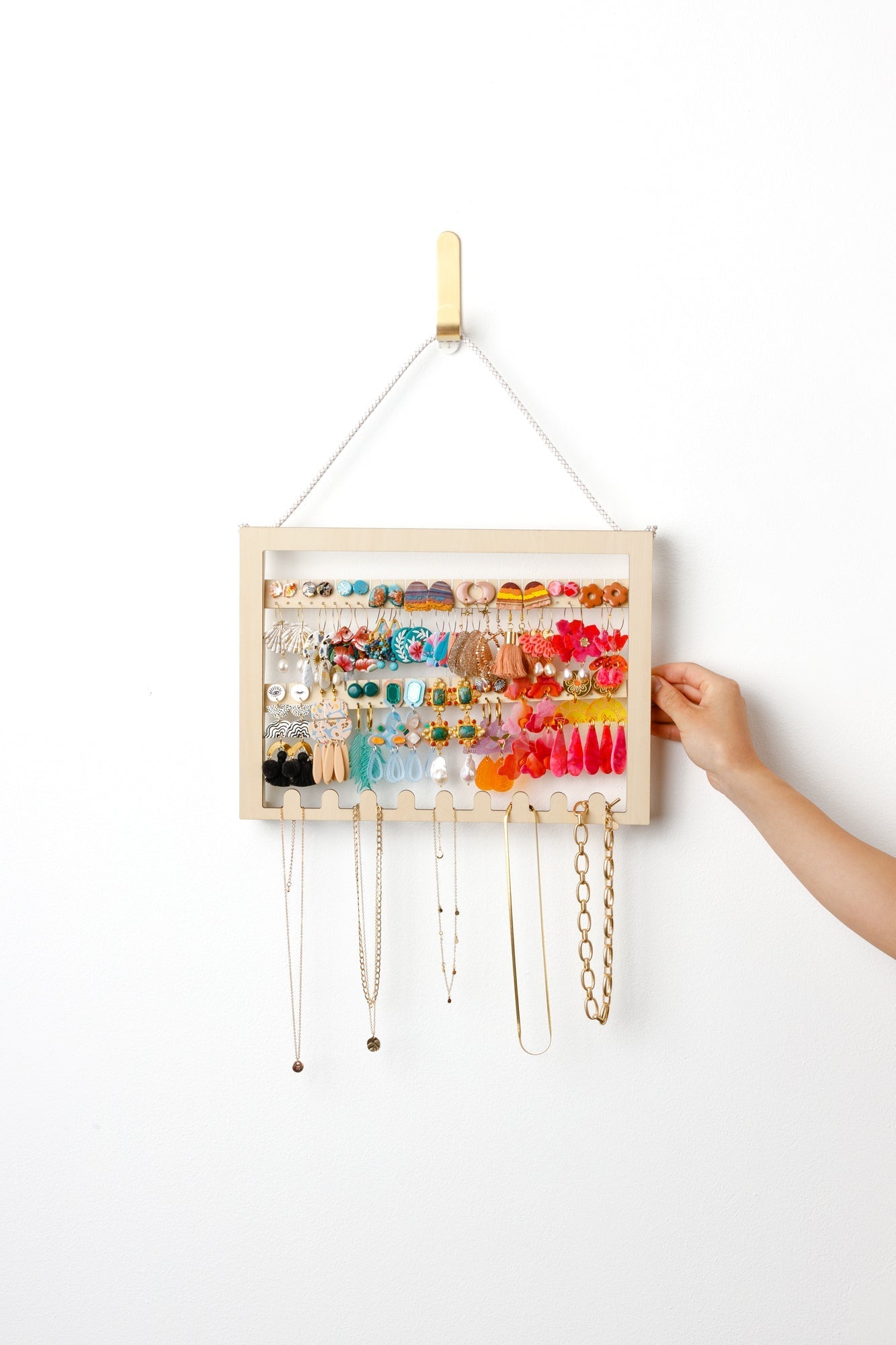 Adjustable earring holder made from wood hanging on a wall