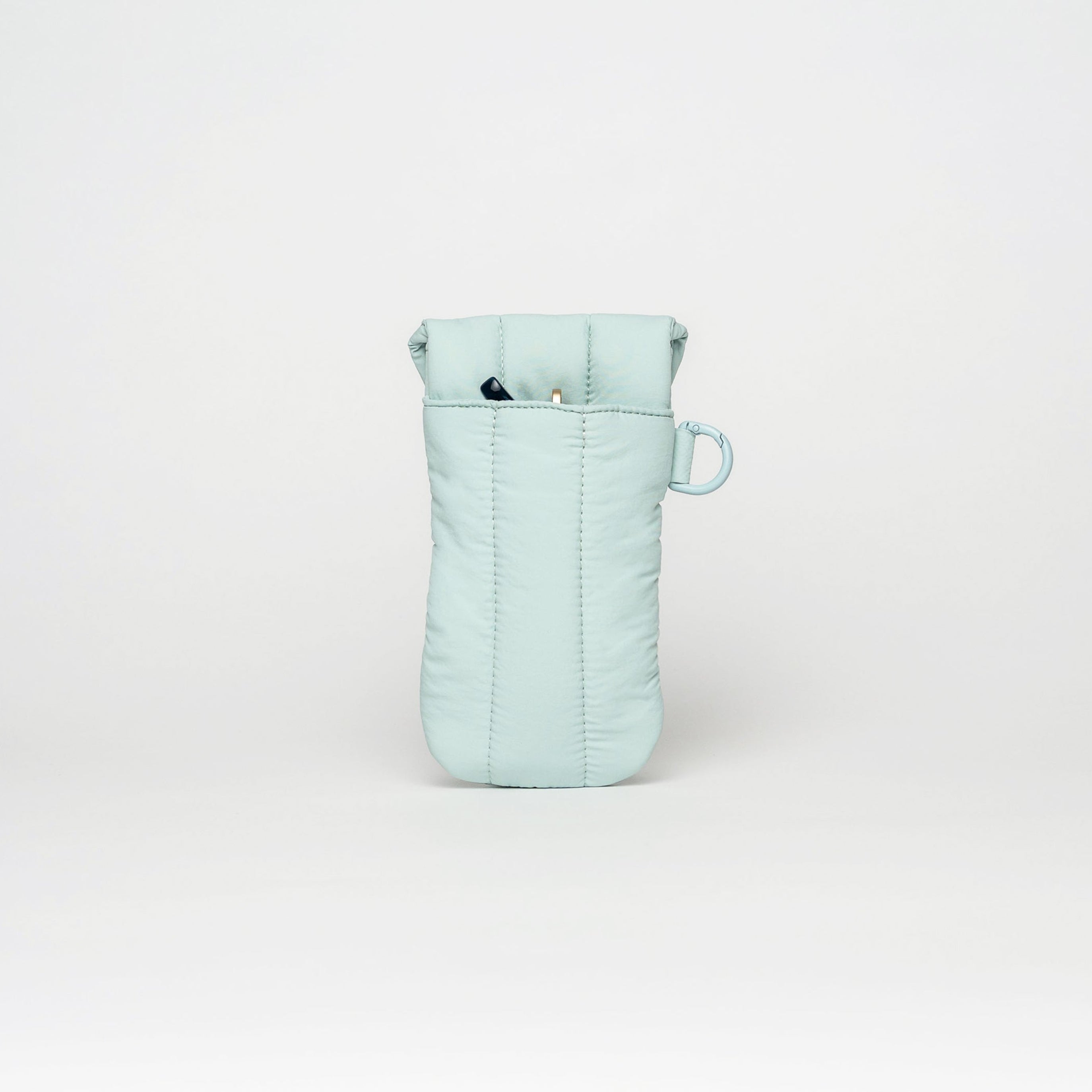 A light mint green quilted pouch or organizer bag with a small matching loop handle, standing upright against a white studio background.