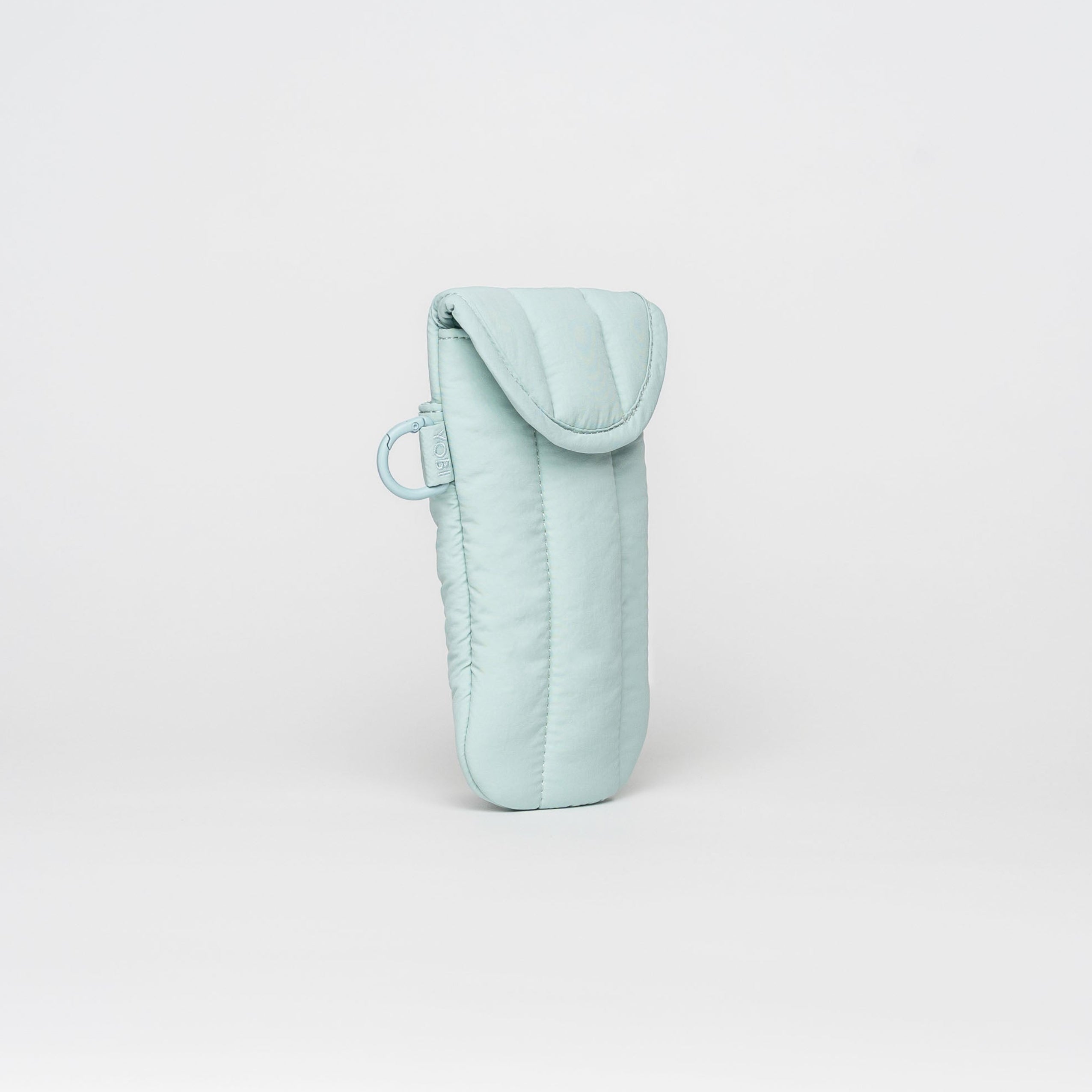 A light mint green quilted fabric pouch with a flap closure and a small matching loop, standing upright on a seamless light gray background.
